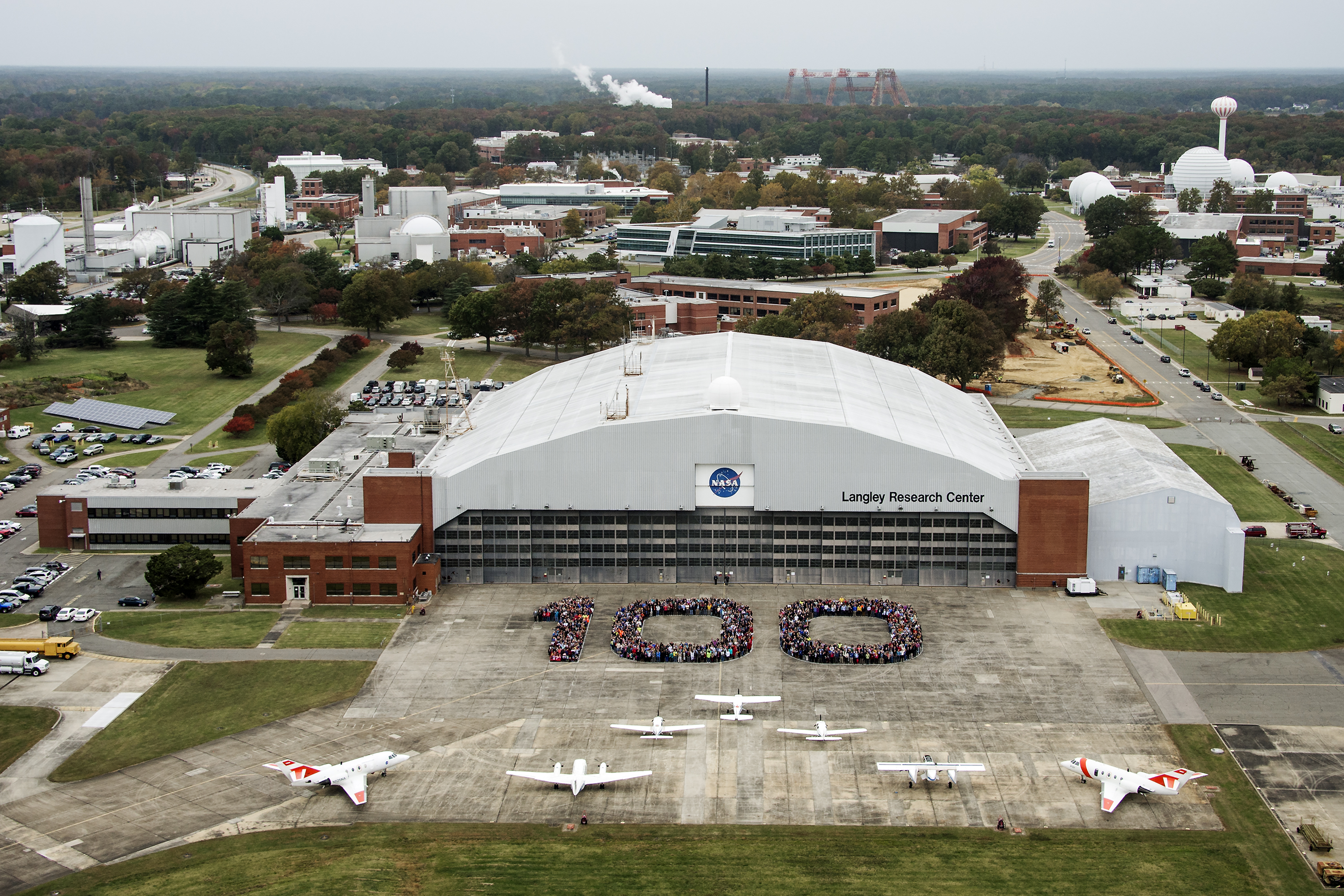 Aerial photos of NASA Langley employees gathered on the back ramp in the shape of 100.